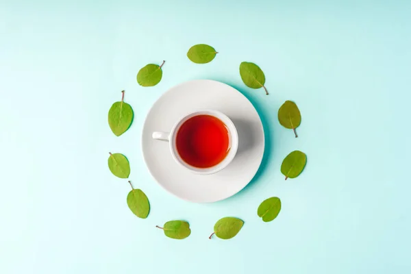 Beautiful minimalist background with green leaves surrounding a cup of tea, space for text