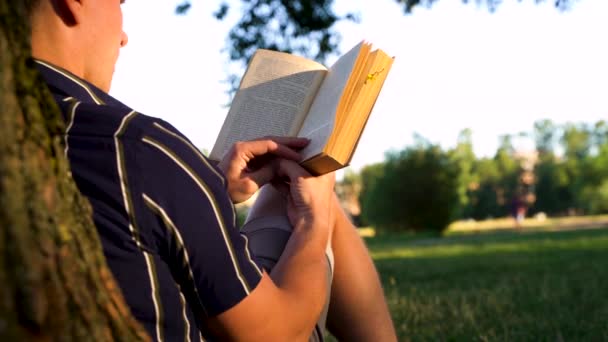 Nagranie Młody Człowiek Siedzi Pod Drzewem Trawie Parku Czyta Książkę — Wideo stockowe