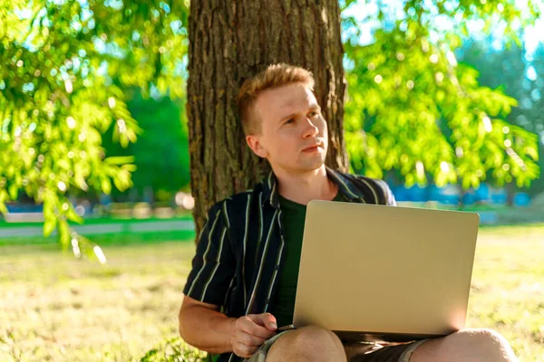 Ein Junger Mann Sitzt Unter Einem Baum Und Arbeitet Mit — Stockfoto
