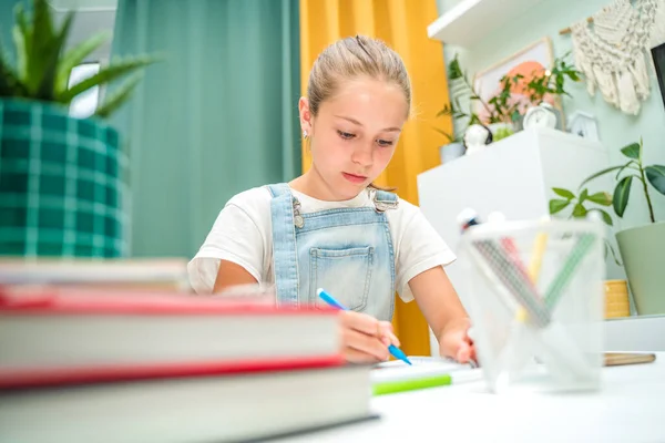 A little girl draws with felt-tip pens at home in a modern living room. Completing homework with the help of books