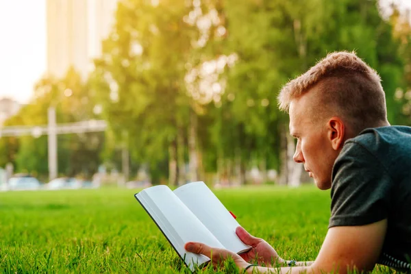 Giovane Uomo Giace Nel Parco Sull Erba Guarda Quaderno Libro — Foto Stock