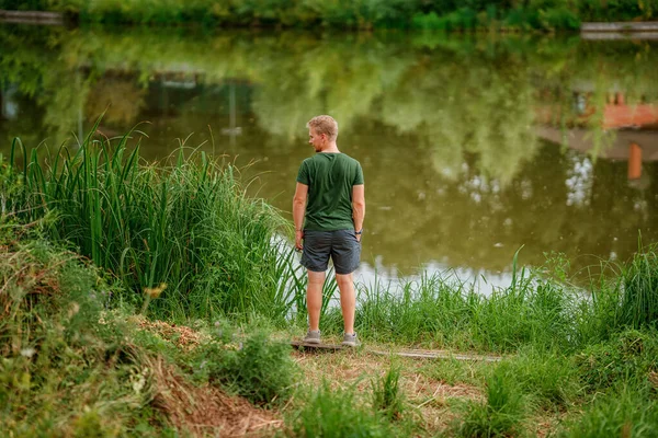 后视镜一个年轻人站在美丽的夏季湖畔 — 图库照片