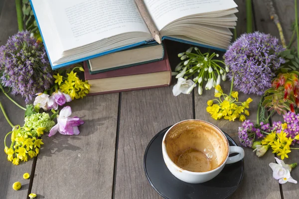 Stilleben med blommor och bok, Tom kaffekopp på trä ba Royaltyfria Stockfoton