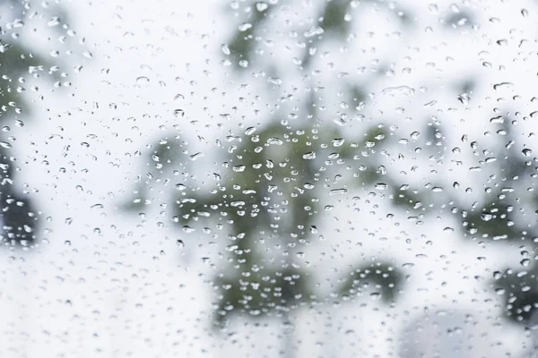 Cae la lluvia sobre la ventana con un fondo — Foto de Stock