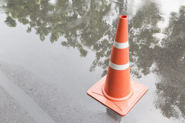 A traffic cone on the road in rain time