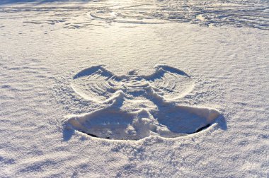 print of a snow angel on fresh white snow and frozen lake at sunset. Abstract background, Christmas, twinter fun, snowy clipart