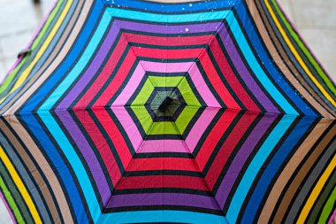 Yağmur damlalarında çok renkli şemsiye, geometrik gökkuşağı deseni, soyut arkaplan, kopyalama alanı