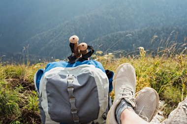 Sırt çantası, yürüyüş direkleri ve spor ayakkabıları vadide bir dağ yürüyüşünde dinlenen genç bir kadın, açık havada aktif sağlıklı bir yaşam tarzı.