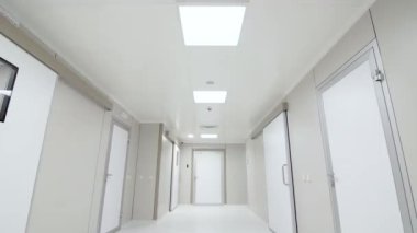 Bir sürü kapalı kapısı olan boş beyaz hastane salonunun görüntüleri.