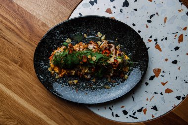 Ahşap arka planda sebzeli ve soslu ızgara somon balığı yakın plan görüntüsü.