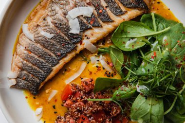 Yakından bakınca soslu ızgara balık ve tabakta otlar görünüyor.