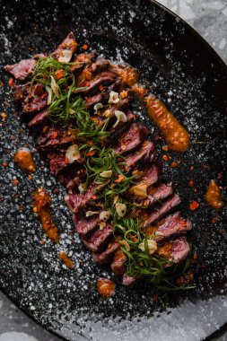 Siyah tabaktaki sosun içindeki lezzetli et parçalarının yakın plan görüntüsü.