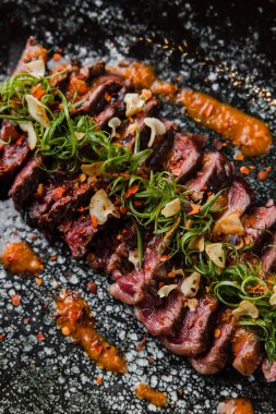 Siyah tabaktaki sosun içindeki lezzetli et parçalarının yakın plan görüntüsü.