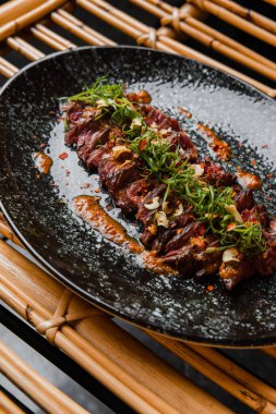 Siyah tabaktaki sosun içindeki lezzetli et parçalarının yakın plan görüntüsü.