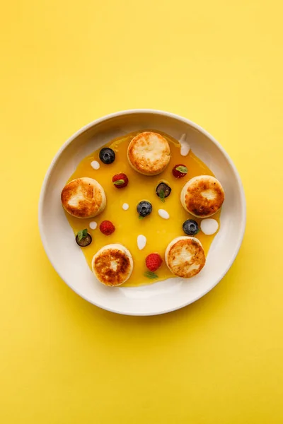 チーズパンケーキとベリーと蜂蜜をホワイトプレートに乗せたおいしい朝食の眺め ストック画像