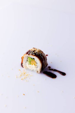 Beyaz zemin üzerinde teriyaki soslu Japon uramaki.