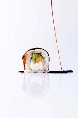 Beyaz zemin üzerinde teriyaki soslu Japon uramaki.