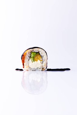 Beyaz zemin üzerinde teriyaki soslu Japon uramaki.