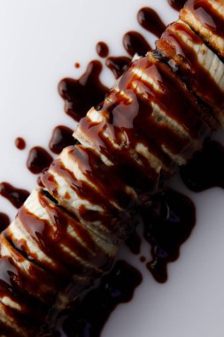 Beyaz zemin üzerinde teriyaki soslu Japon uramaki.