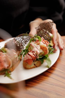 Beyaz tabakta somon, sos ve sebzeli bruschetta manzarası