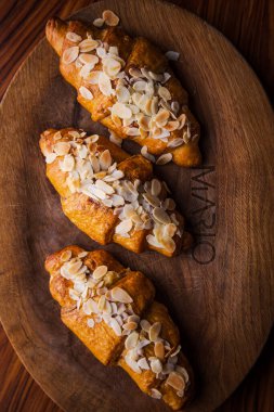 Tahta üzerinde çıtır kruvasan ve badem kırıntıları.