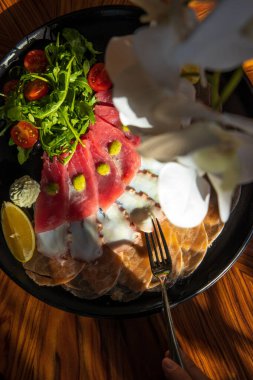 Lezzetli deniz ürünleri ve limon dilimlenmiş tabak, otlar, ahtapot dokunaçları, somon parçaları ve eski ahşap bir masada kırmızı balık filetosu.