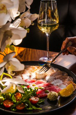 Lezzetli deniz ürünleri ve limon dilimlenmiş tabak, otlar, ahtapot dokunaçları, somon parçaları ve eski ahşap bir masada kırmızı balık filetosu.