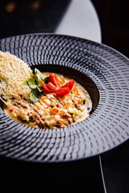 Kuşkonmaz ve domates dilimli leziz kremalı pirinç ahşap arka planda peynirin soyut desenleri.