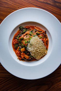 Domates soslu koyu spagetti bolonez ve peynirin soyut deseniyle süslenmiş sarımsak.