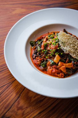 Domates soslu koyu spagetti bolonez ve peynirin soyut deseniyle süslenmiş sarımsak.