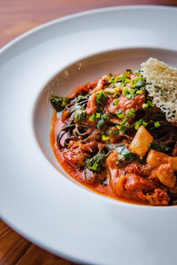 Domates soslu koyu spagetti bolonez ve peynirin soyut deseniyle süslenmiş sarımsak.