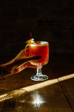 Kadın eli taze pembe bir kokteyl tutuyor.