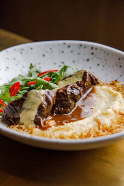 Soslu peynirli biftek ve patates püresinin yakın plan görüntüsü.