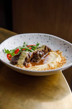 Soslu peynirli biftek ve patates püresinin yakın plan görüntüsü.