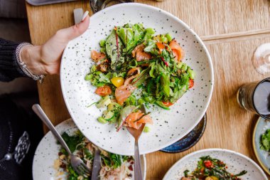 Somon salatasının yakın görüntüsü ve çeşitli yemeklerle servis edilen bir masa.