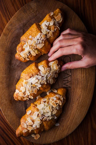Köstliche Knusprige Croissants Auf Holzbrett Warmem Licht Mit Mandelkrume lizenzfreie Stockfotos