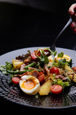 Siyah tabakta yumurta ve lezzetli salatanın yakın görüntüsü.