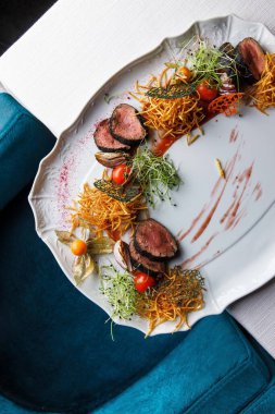 Tabağında patates ve sebze olan et madalyonlarının yakın plan görüntüsü.