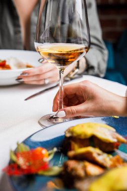 Servis masasında şarap kadehleriyle oturan insanların görüntüsü.