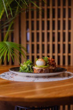 Tostun yakın plan görüntüsü. Tabağında domates dilimi ve börek var.