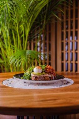 Tostun yakın plan görüntüsü. Tabağında domates dilimi ve börek var.