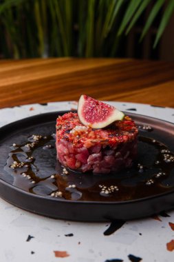 Kırmızı soslu ve incirli Tartarus tabağının yakın görüntüsü.