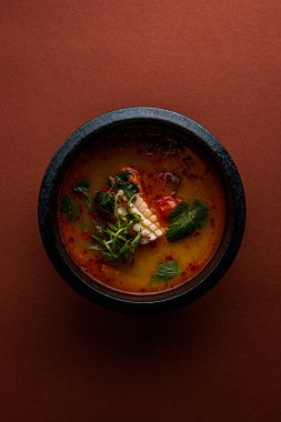Kırmızı arka planda deniz mahsulleri olan Asya çorbasının yakın plan görüntüsü.