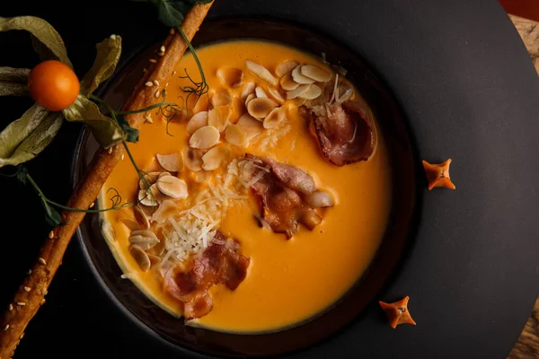 Closeup View Pumpkin Soup Bacon Sesame Straw Dark Plate Royalty Free Stock Images