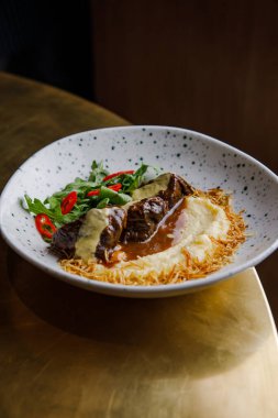 Soslu peynirli biftek ve patates püresinin yakın plan görüntüsü.