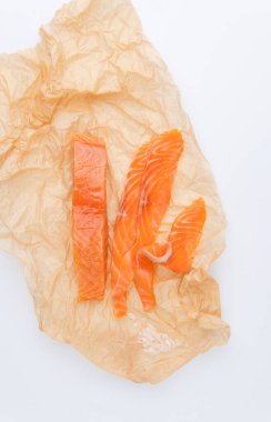 Kırmızı balık parçalarının beyaz arkaplanda buruşuk kağıt üzerindeki üst görünümü