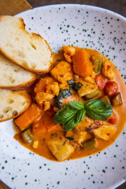 Deniz ürünleri ve ekmek dilimleriyle pişirilmiş sebzelerin yakın plan görüntüsü.