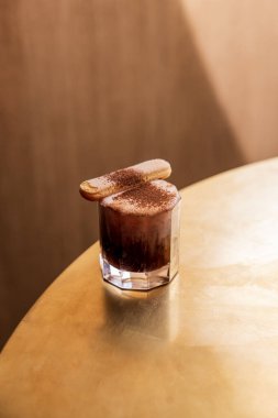 Çikolata tozu ve Savoiardi kurabiyesiyle süslenmiş tiramisu tadı olan bir kokteyl.