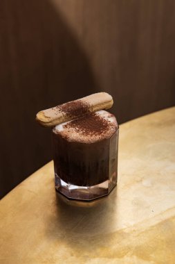 Çikolata tozu ve Savoiardi kurabiyesiyle süslenmiş tiramisu tadı olan bir kokteyl.
