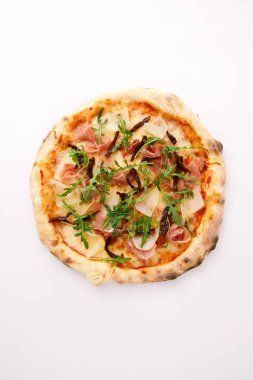 Beyaz zemin üzerinde roka ve jamon bulunan ev yapımı pizzanın üst görünümü  